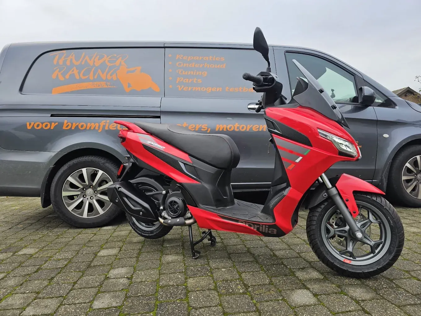 Rode Aprilia-scooter voor de bestelwagen van Thunder Racing in Geel