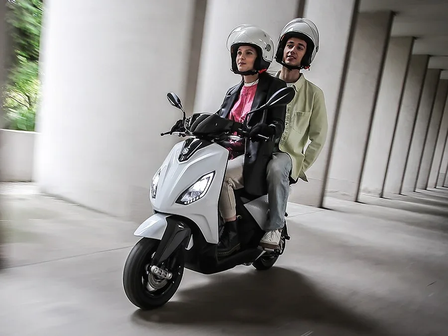 Piaggio 1 elektrische scooter in het wit met twee personen in de stad