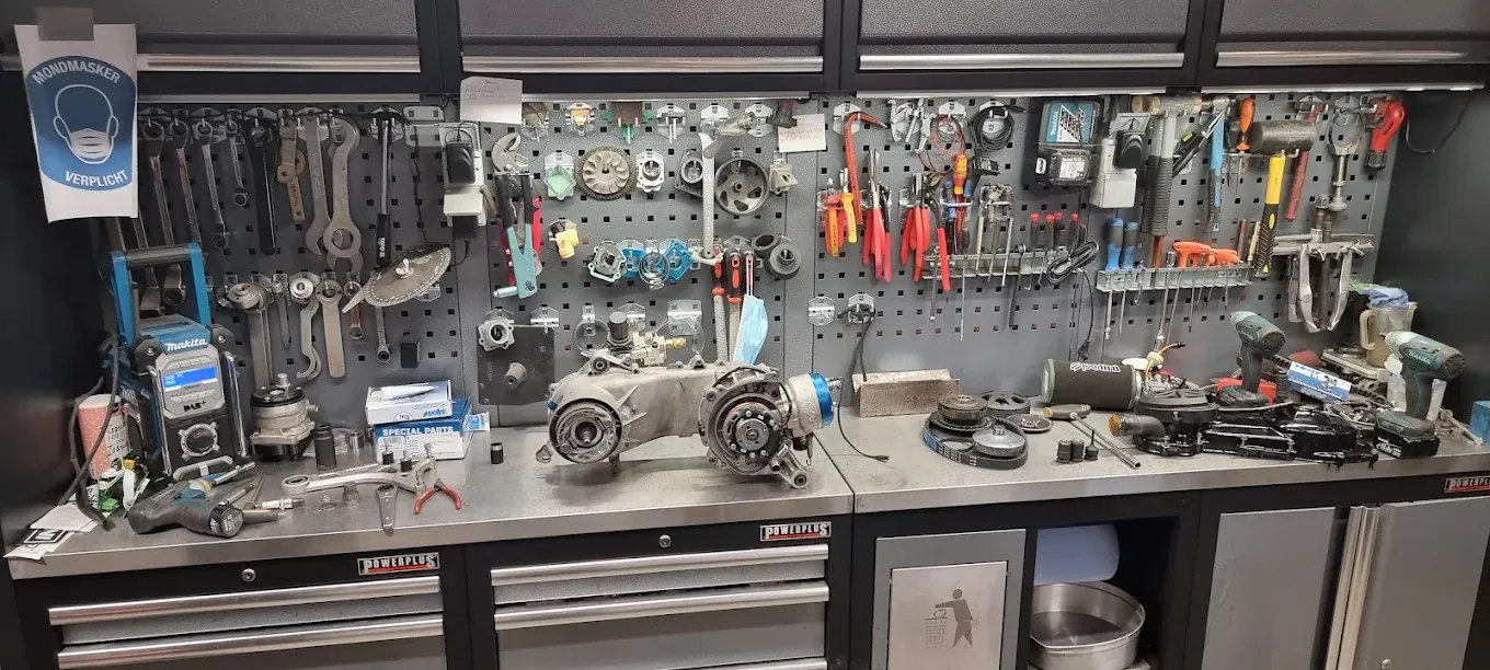 Werkbank met een gedemonteerd scootermotorblok bij Thunder Racing